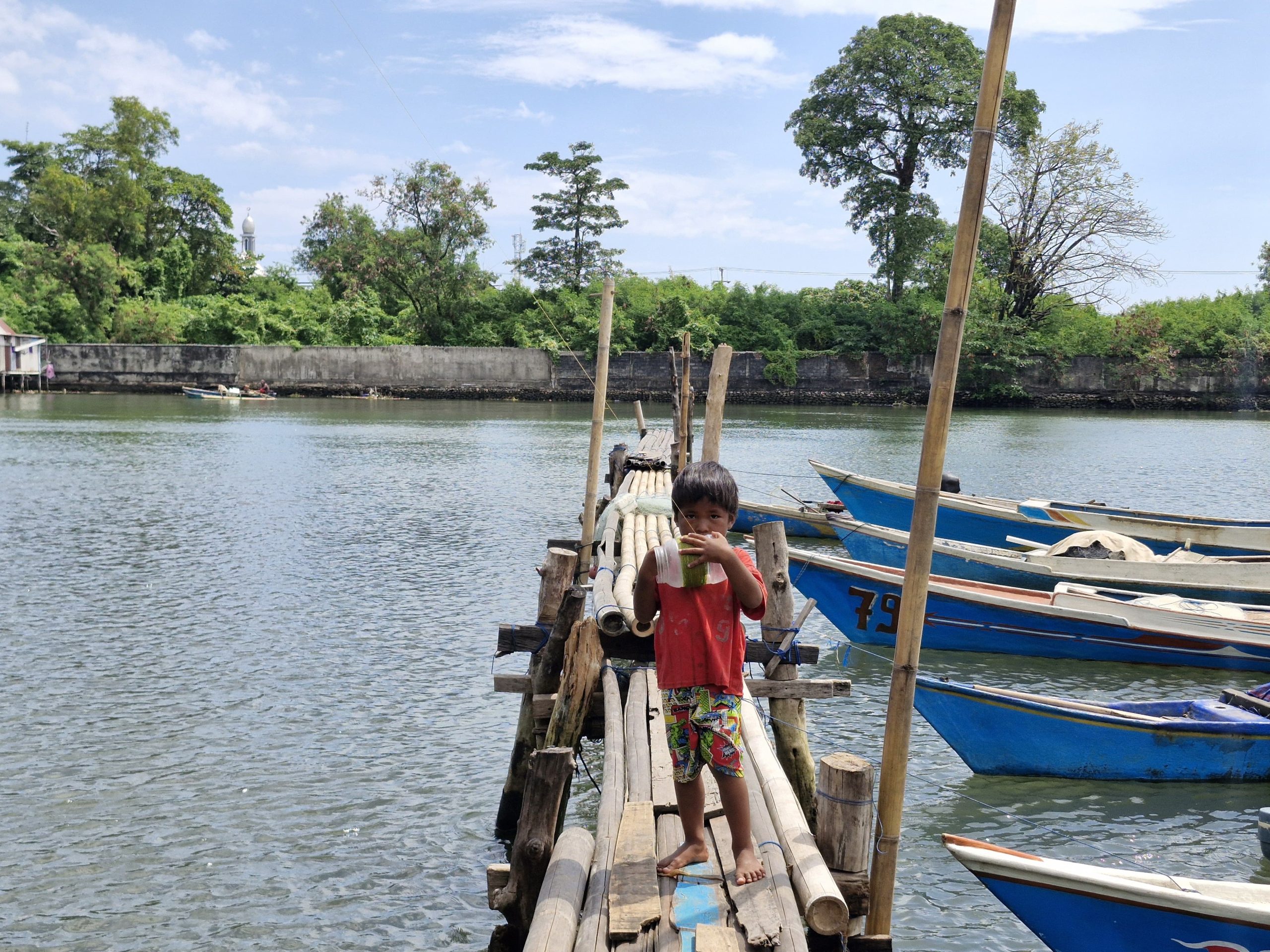 Seorang anak memegang kaleng yang digunakan sebagai wadah melilit benang layangan di Kampung Kaserokang, Tamalanrea, Makassar